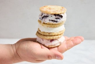 Three sandwich bread ice cream sandwiches stacked on top of each other in a baker's hand